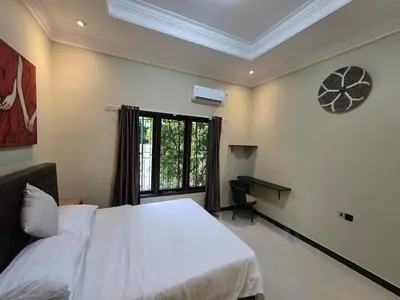 a bedroom with a bed and a window and a desk at Happy's house Bali in Kerobokan