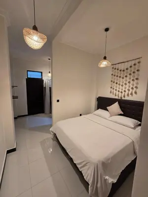 a bedroom with a large bed with two lights at Happy's house Bali in Kerobokan