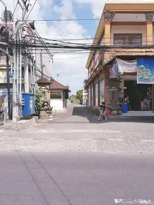 a person sitting on the side of a street next to a building at Happy's house Bali in Kerobokan