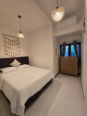 a bedroom with a large bed and two lights at Happy's house Bali in Kerobokan