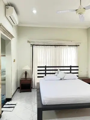 a bedroom with a large white bed and a window at Kubu In Dhana Sanur Guest House in Mantaak