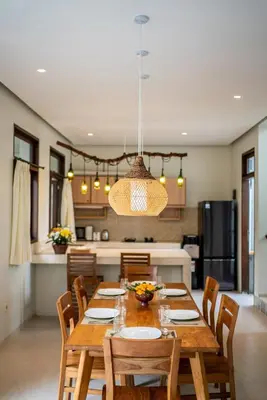 a dining room and kitchen with a wooden table and chairs at Tropical 3BR Oasis w Private Pool Villa Nau Mai in Seminyak