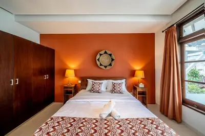 a bedroom with a large bed with orange walls at Tropical 3BR Oasis w Private Pool Villa Nau Mai in Seminyak