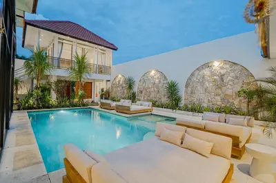 a house with a swimming pool with white furniture at Villa Orchid Heaven by Bali Villa Solutions in Seminyak