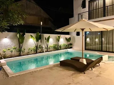 a swimming pool with a chair and an umbrella at Dakings Greece House in Legian