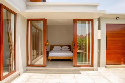 a bedroom with a bed and two glass doors at Rumah Melissa - Modern Boho 3BR Brand New Villa in Sanur in Sanur
