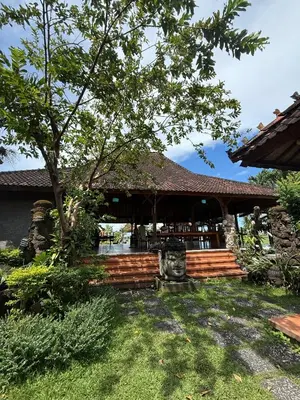 a building with a porch with a tree in the yard at Balian Retreat Centre Homestay in Sanur