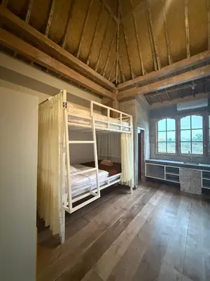 a bedroom with bunk beds in a room with wooden floors at Balian Retreat Centre Homestay in Sanur