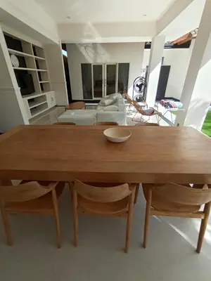 a wooden table and chairs in a living room at Villa Bu H in Kerobokan