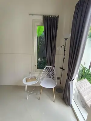 a room with a window and a chair and a mirror at Villa Bu H in Kerobokan