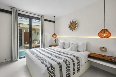 a white bedroom with a bed and a window at Kirelo Villa by Kozystay - Sanur in Sanur