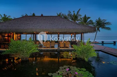 a resort with a pool and chairs and the ocean at The Koral by Kozystay - Seminyak in Kuta