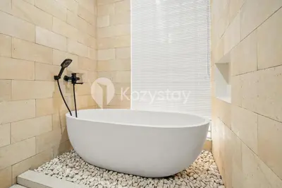 a bath tub in a bathroom with rocks at Sadin Villa by Kozystay - Umalas in Kerobokan