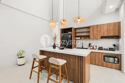 a kitchen with wooden cabinets and a counter with stools at Sadin Villa by Kozystay - Umalas in Kerobokan