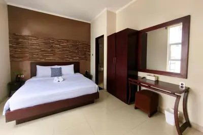 a bedroom with a large bed and a mirror at Domaxo Villa in Seminyak