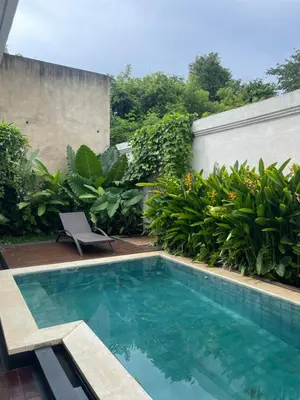 a swimming pool in a yard with a chair and plants at Ariani Villa in Jimbaran