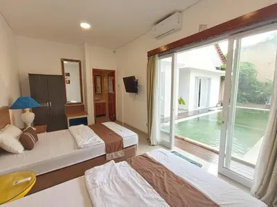 a bedroom with two beds and a large window at Ariani Villa in Jimbaran