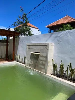 a pool of water next to a house at Villa Damai in Sanur