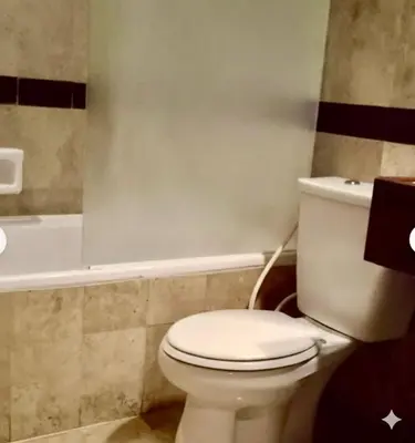 a bathroom with a white toilet and a bath tub at Jayakarta Service Apartments in Seminyak