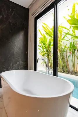 a bath tub in a bathroom with a window at Anoya Boutique Villa in Kerobokan