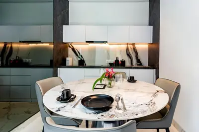 a dining room table with chairs and a white kitchen at Anoya Boutique Villa in Kerobokan