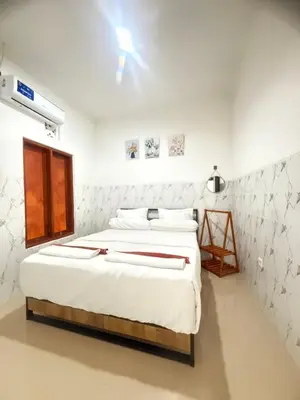 a bedroom with a large bed with white sheets at Private Room Near Sanur Beach Bali in Sanur