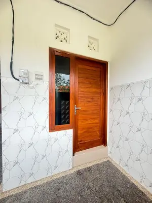 a wooden door in a room with white walls at Private Room Near Sanur Beach Bali in Sanur