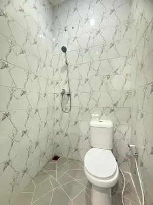 a bathroom with a toilet and a tiled wall at Private Room Near Sanur Beach Bali in Sanur
