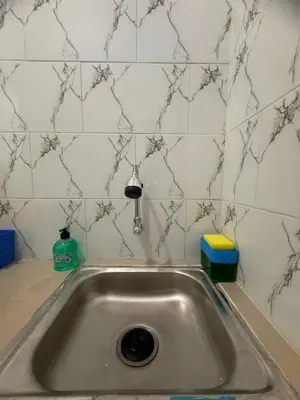 a stainless steel sink in a kitchen with white tiles at Private Room Near Sanur Beach Bali in Sanur