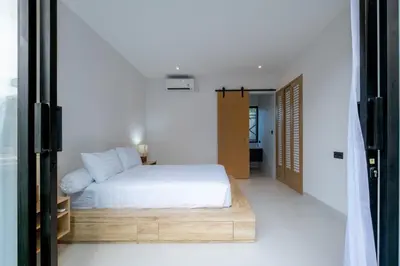 a bedroom with a white bed with a wooden platform at Villa Seminyak Beachside Luxury in Seminyak