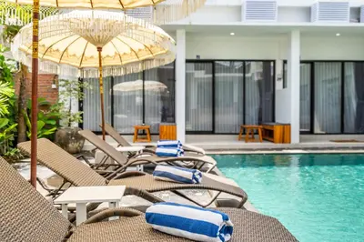 a group of chairs and umbrellas next to a swimming pool at Uma Katani in Jimbaran