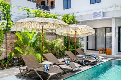 a group of chairs and umbrellas next to a swimming pool at Uma Katani in Jimbaran