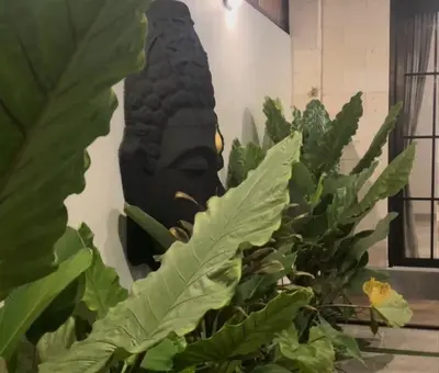 a statue of a head behind some green plants at FrangipaniVilla in Seminyak