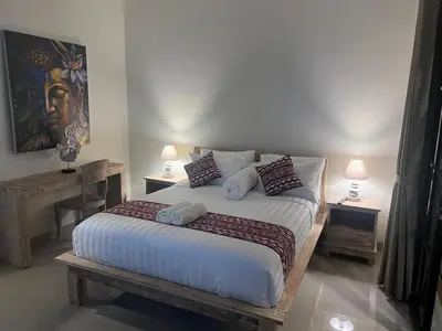 a bedroom with a bed with two tables and two lamps at FrangipaniVilla in Seminyak
