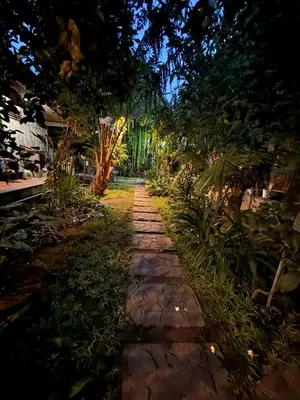 a stone path in a garden at night at The Secreet Garden Hotel in Denpasar
