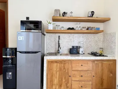 a kitchen with a stainless steel refrigerator and wooden cabinets at House of Rakiki Legian - 2BR Private Pool Villa in Central Legian close to Beach in Legian