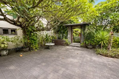 a patio in front of a house with a tree at Palm 57 Guest House Legian in Legian