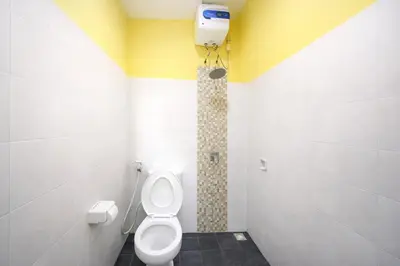 a bathroom with a toilet and a shower at Palm 57 Guest House Legian in Legian