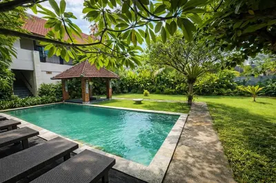a swimming pool in a yard with a gazebo at Palm 57 Guest House Legian in Legian