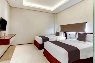 a hotel room with two beds and a tv at Collection O Legian Near Pantai Kuta Formerly Premium Legian in Legian