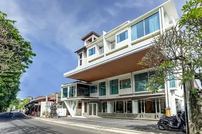 a tall white building with windows on a street at Collection O Legian Near Pantai Kuta Formerly Premium Legian in Legian