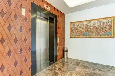 a glass elevator in a room with a painting on the wall at Collection O Legian Near Pantai Kuta Formerly Premium Legian in Legian