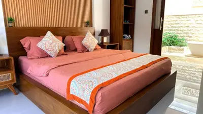 a bedroom with a large bed with pink sheets and pillows at Emstaliese & Palmarosa Villas Seminyak in Legian