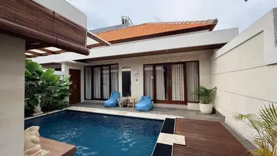 a swimming pool in front of a house at Emstaliese & Palmarosa Villas Seminyak in Legian