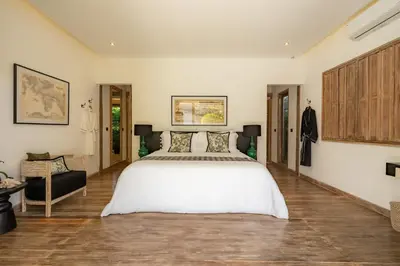 a bedroom with a large white bed and a chair at Luxe Bali Seminyak Villa by Betterplace in Seminyak