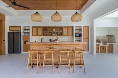 a kitchen with a wooden counter and stools at Villa Selena Space Luxury 4BR 15m Pool BBQ Staffed in Seminyak
