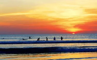 a group of people surfing in the ocean at sunset at Villa Batu, Superb 4BR beachside in Canggu