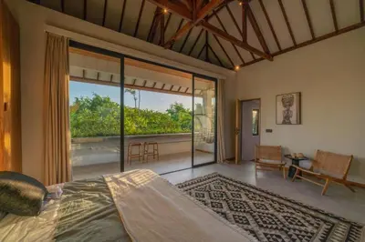 a bedroom with a bed and a large glass window at Villa Batu, Superb 4BR beachside in Canggu