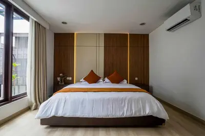 a bedroom with a large bed and a large window at Norm Villa Kuta in Kuta