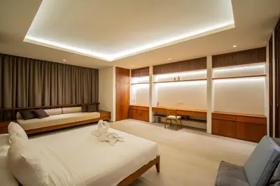 a bedroom with a bed and a couch and a chair at Luxury Rosa Village - 4 Bedrooms Walkable to Beach in Jimbaran